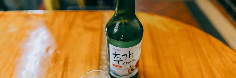 A bottle of soju with a shot glass